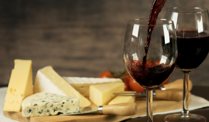 Planche de fromages avec variation de fromages et deux verres à vin rouge