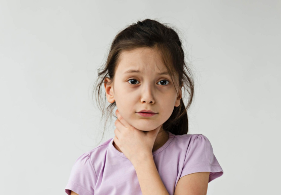 Une fille se tient le cou à cause d'un mal de gorge.