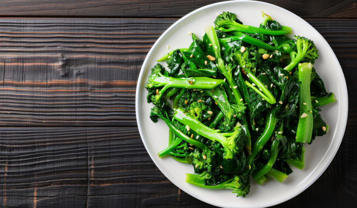 Vue du ciel, une assiette blanche remplie de brocolis cuits à la vapeur est posée sur une table en bois foncé.